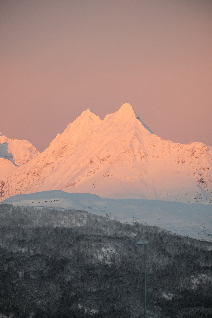 Snow-covered mountain peaks in warm pink light